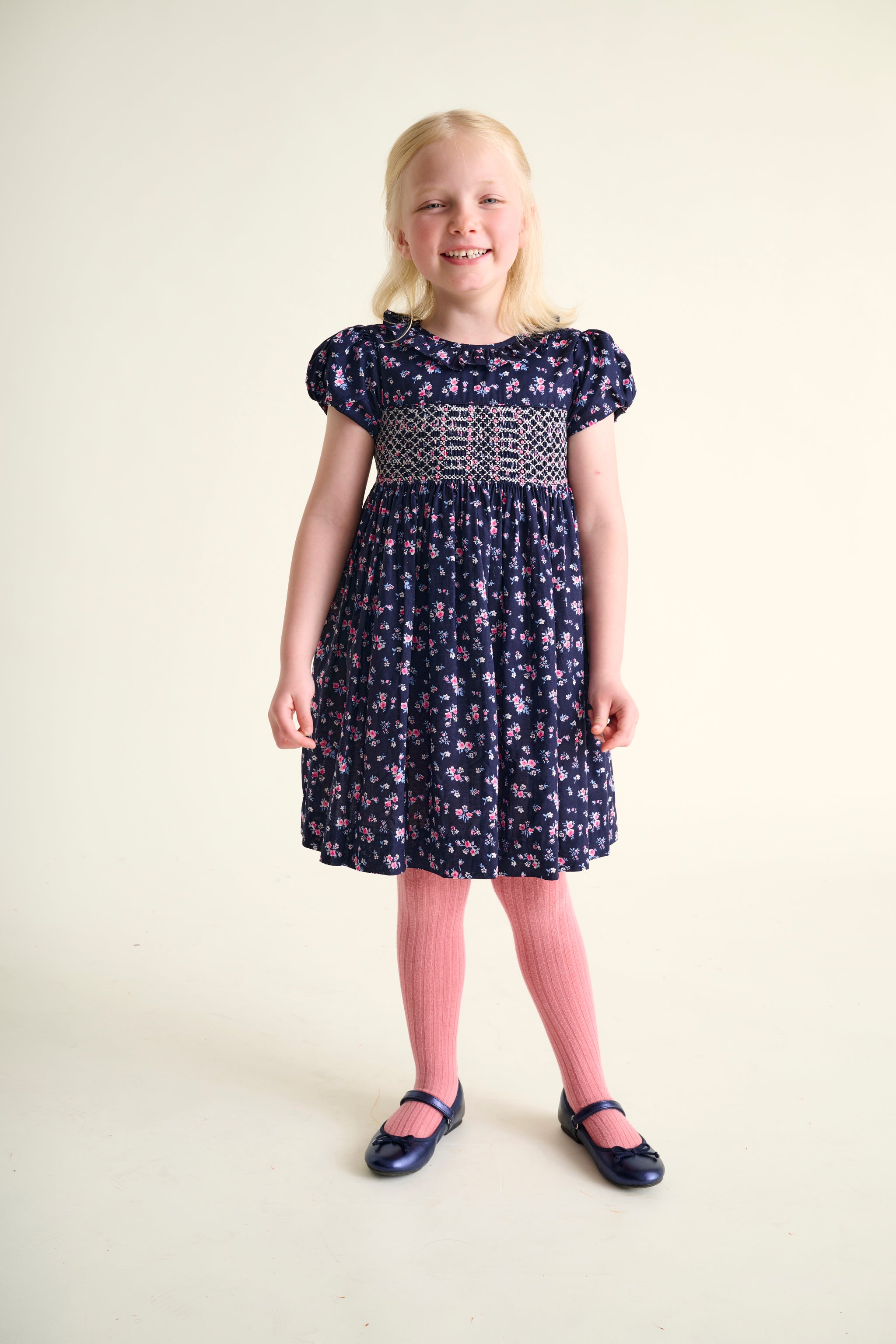Young girl wearing a  navy and pink floral dress with a hand-smocked bodice
