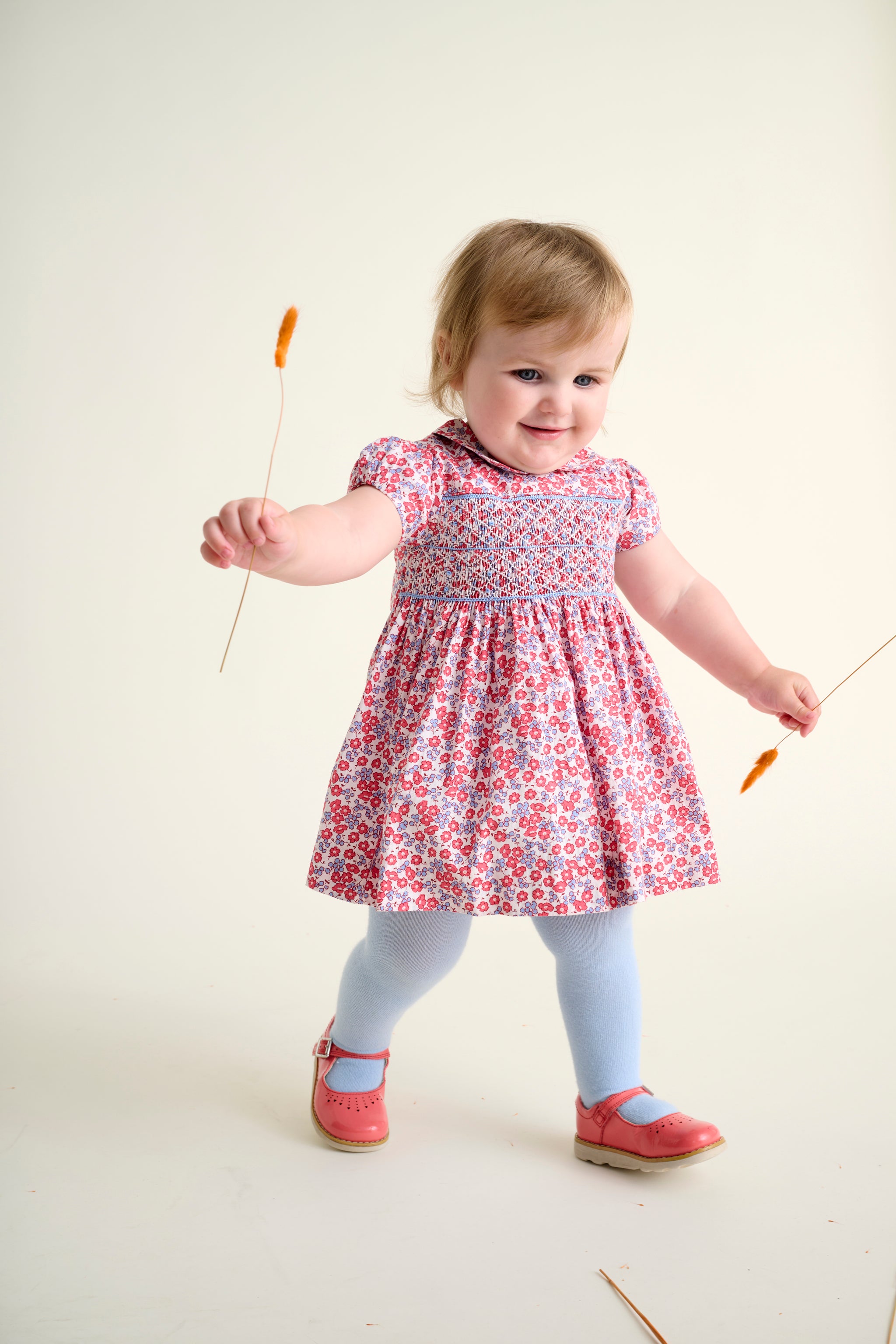 Toddler girl in a floral dress playing
