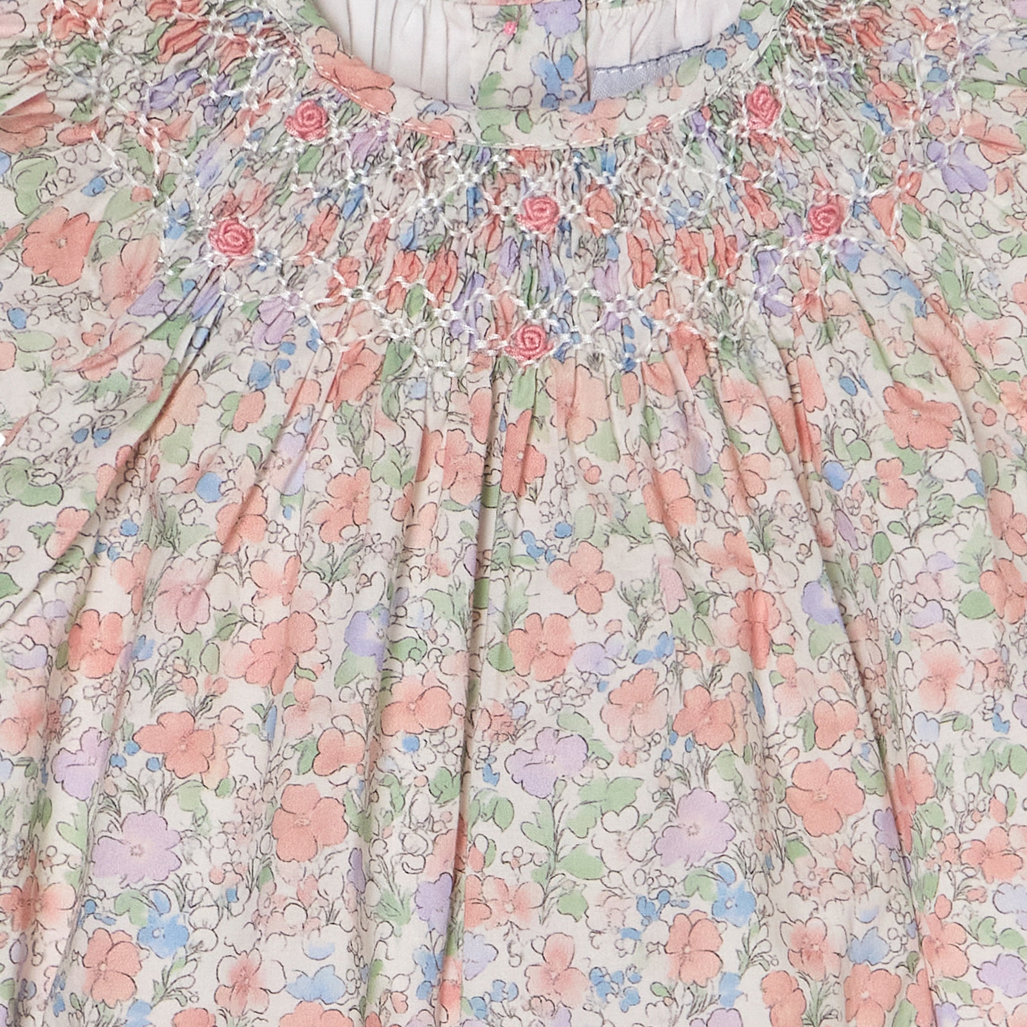 Floral patterned romper with a soft color palette and hand-smocking