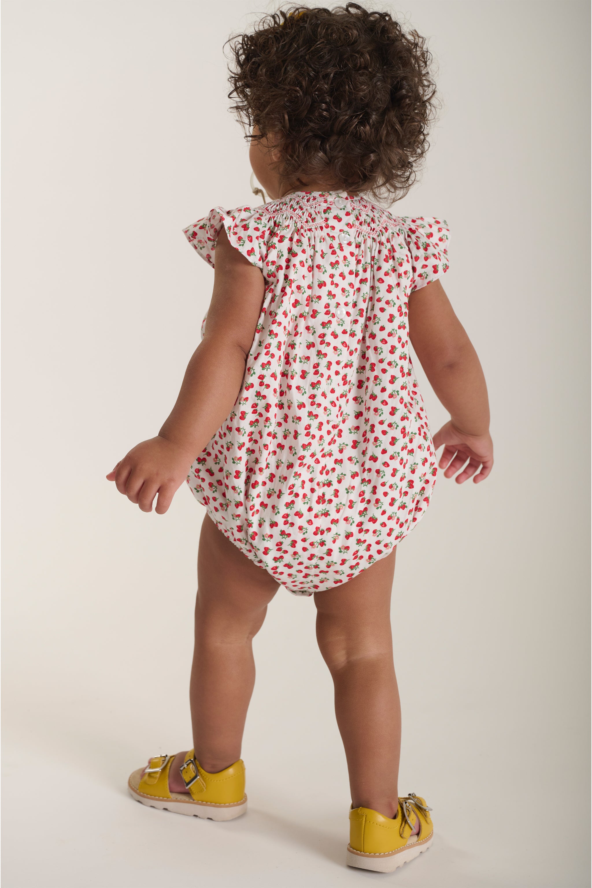 baby in strawberry romper back view