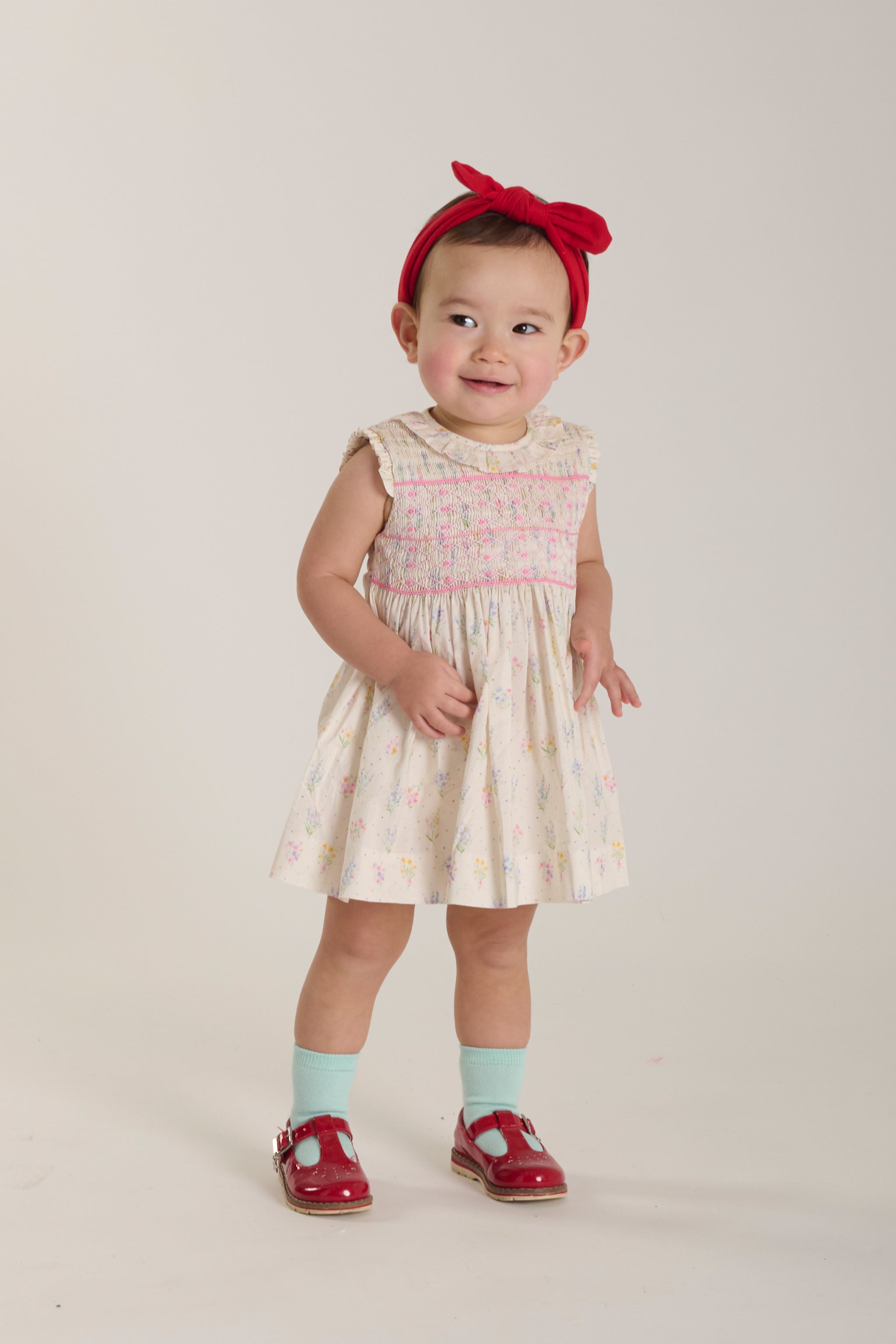 baby standing  wearing pastel wildflower smocked summer dress
