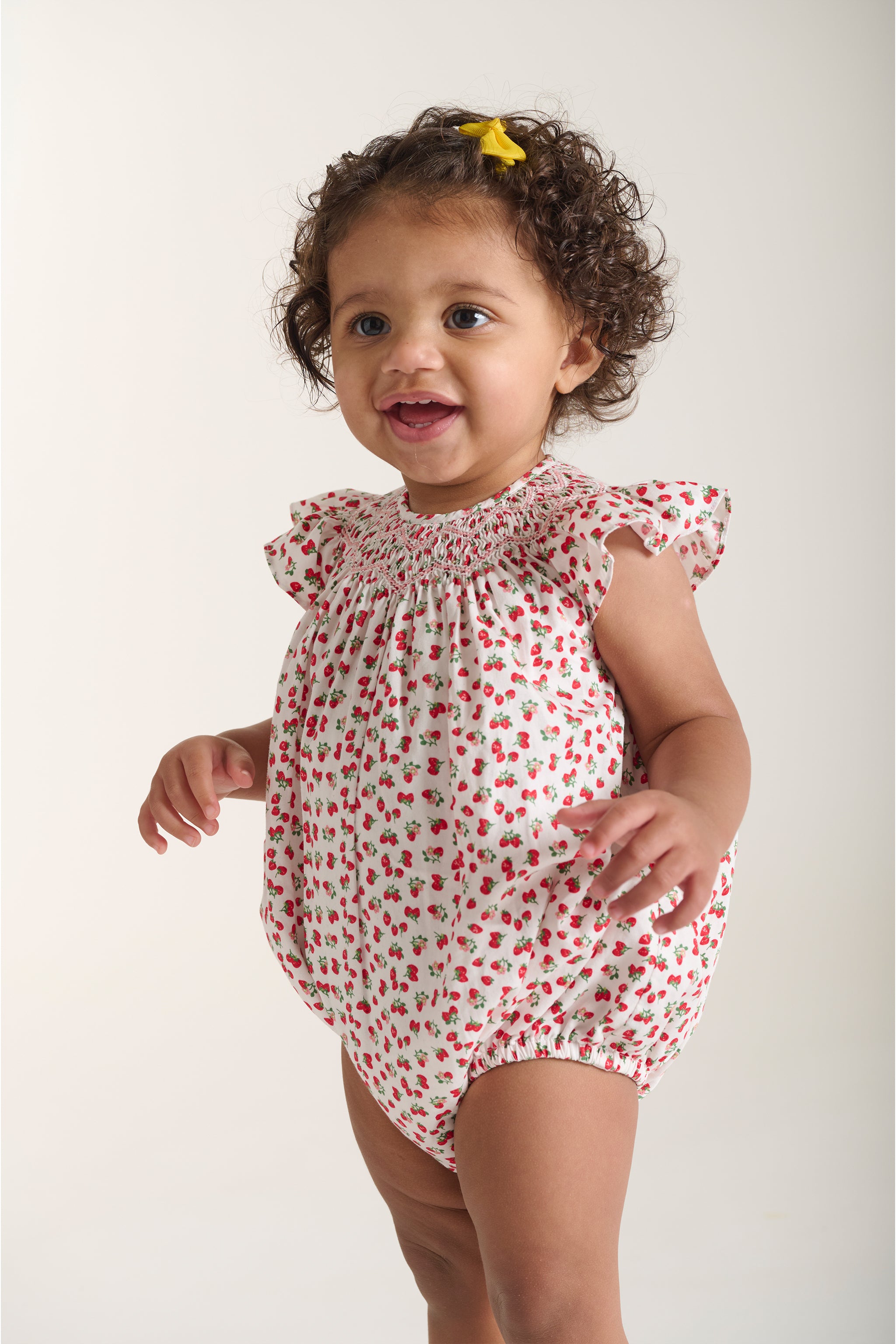 Baby wearing a strawberry print romper closeup