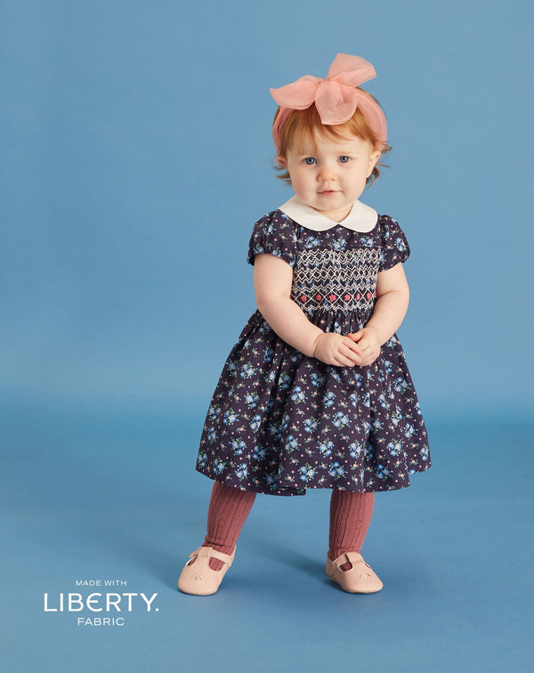 baby in navy smock dress made with Liberty fabrics