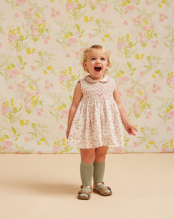 toddler wearing smocked baby dress, sleeveless, floral design