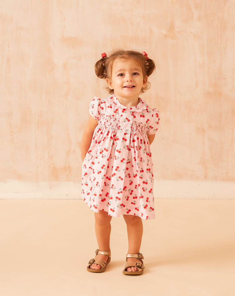 baby in cherry print smock dress