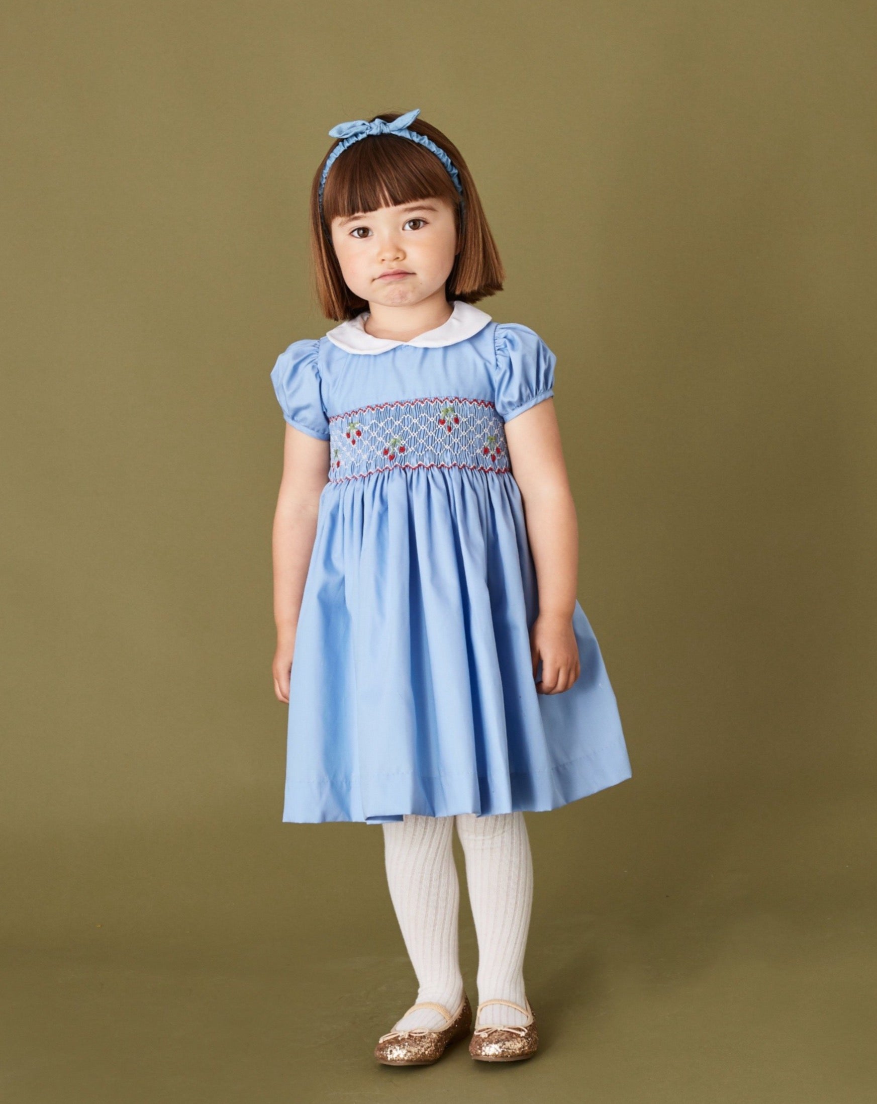girl in pale blue hand smocked dress with cherry embroidery